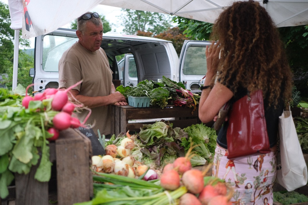 A woman buys fresh vegetables at the farmers market